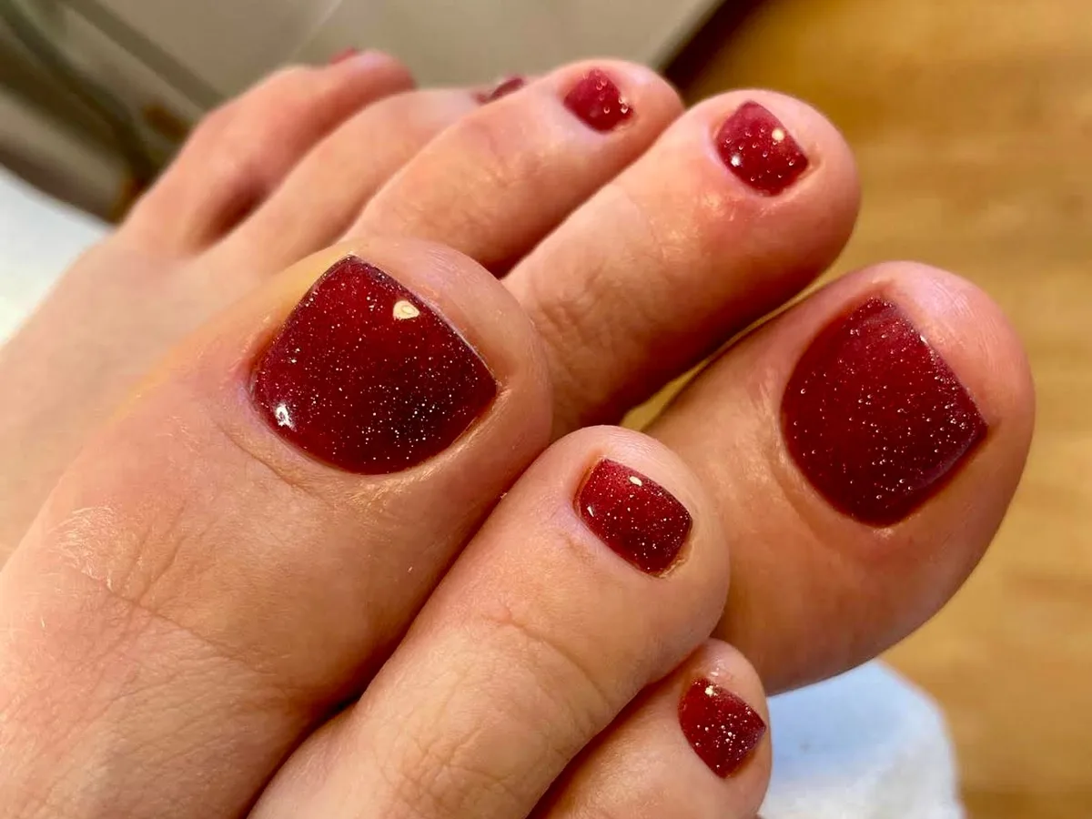 Fußpflege mit langanhaltendem Shellac in funkelndem Dunkelrot